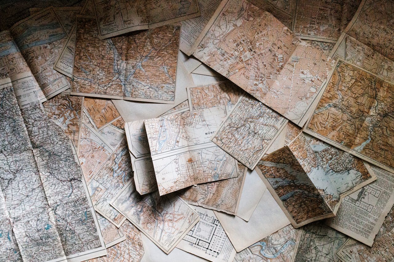 Home A collection of vintage maps scattered for exploring world journeys and discoveries.